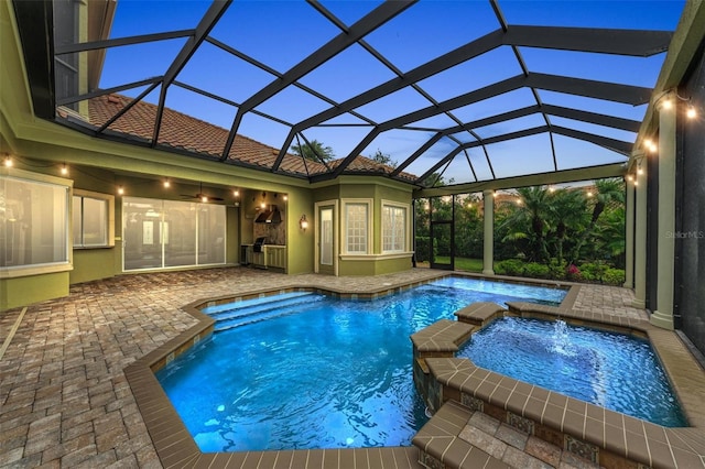 pool at dusk with an in ground hot tub, a patio area, and a lanai