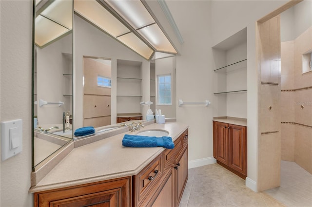 bathroom with a tile shower, vanity, and tile patterned floors