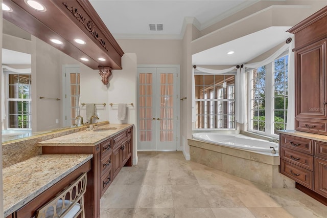 bathroom with tiled bath, french doors, crown molding, and vanity