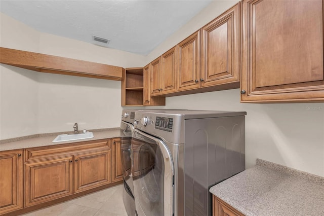 laundry room with cabinets, sink, independent washer and dryer, light tile patterned floors, and a textured ceiling