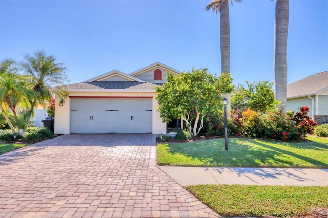 view of front of home with a front yard, decorative driveway, an attached garage, and stucco siding