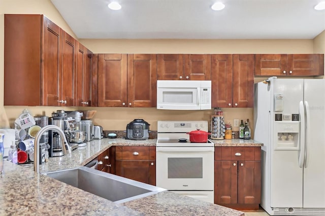 kitchen with light stone countertops, white appliances, vaulted ceiling, and sink