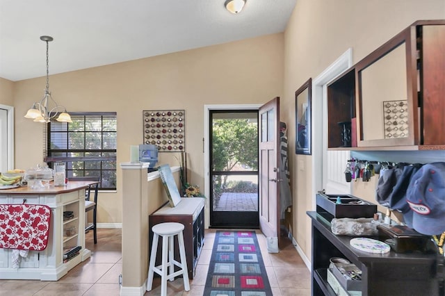 foyer entrance featuring a wealth of natural light, light tile patterned floors, a chandelier, and lofted ceiling