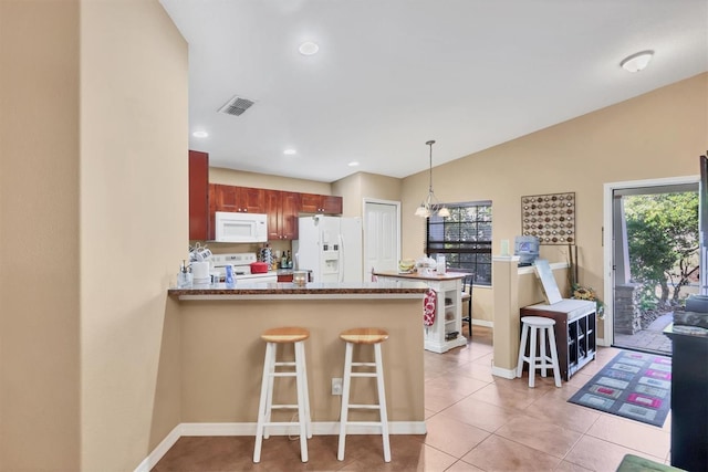 kitchen featuring hanging light fixtures, kitchen peninsula, vaulted ceiling, white appliances, and a kitchen bar