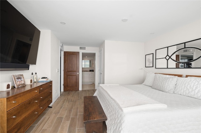 bedroom with connected bathroom and light wood-type flooring