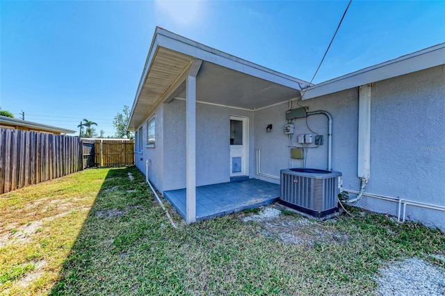 exterior space with central AC unit, a patio, and a lawn