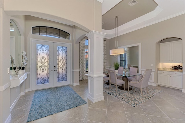 entryway with french doors, ornate columns, crown molding, and light tile patterned flooring