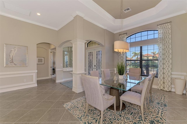 dining space featuring a high ceiling, french doors, tile patterned floors, crown molding, and decorative columns