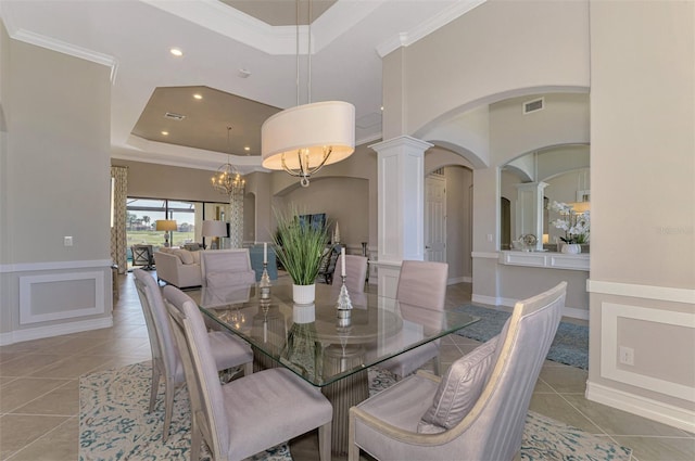 dining room with a notable chandelier, ornate columns, light tile patterned floors, and a tray ceiling