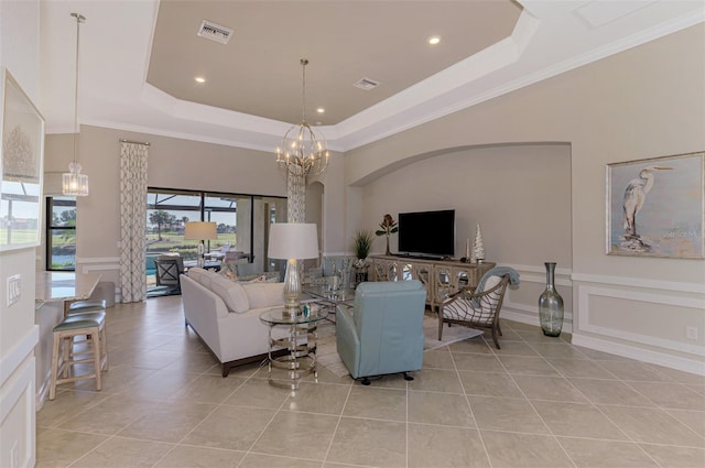 tiled living room featuring a raised ceiling, ornamental molding, and a chandelier