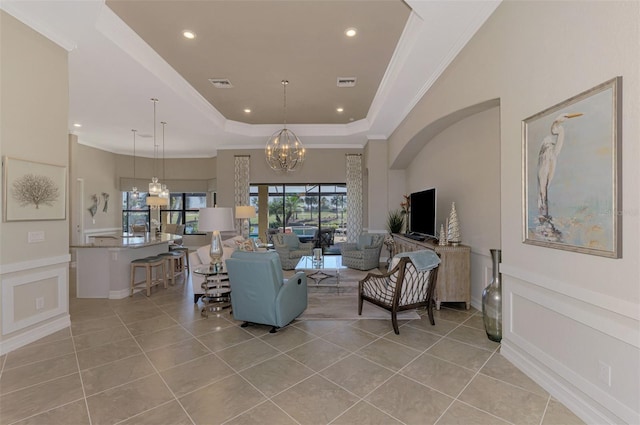 living room with a raised ceiling, ornamental molding, light tile patterned floors, and an inviting chandelier