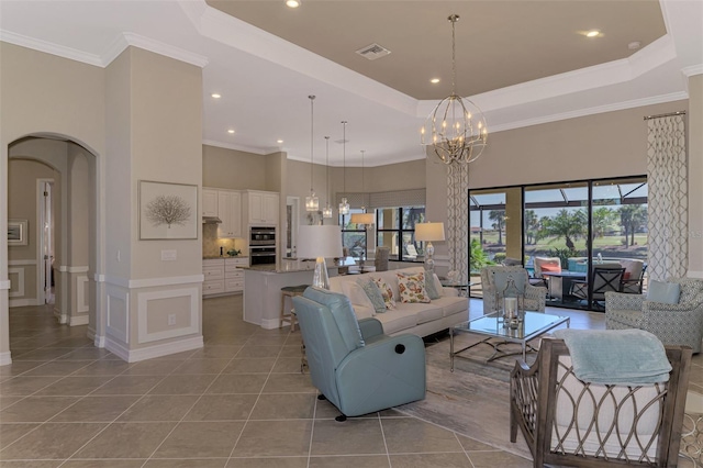 living room with a chandelier, light tile patterned floors, a towering ceiling, and crown molding