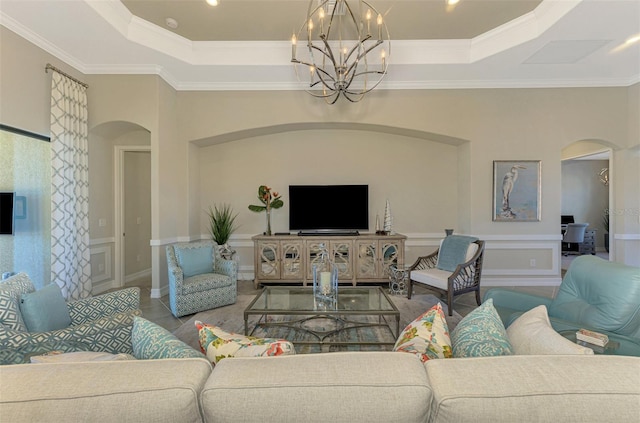 living room with crown molding, a tray ceiling, and an inviting chandelier