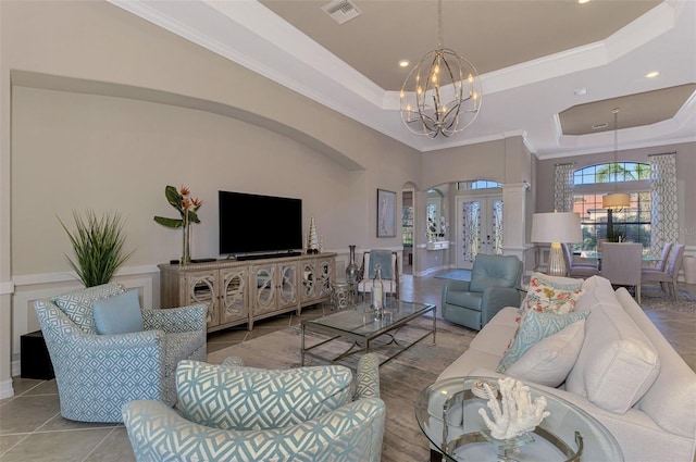 living room featuring light tile patterned floors, a raised ceiling, a notable chandelier, and crown molding