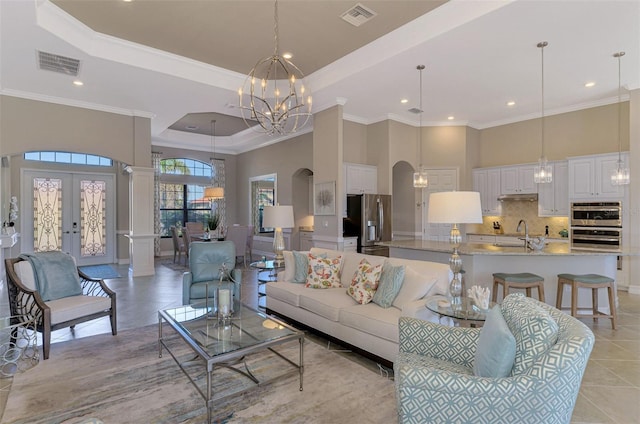 living room with french doors, a notable chandelier, ornamental molding, and light tile patterned flooring