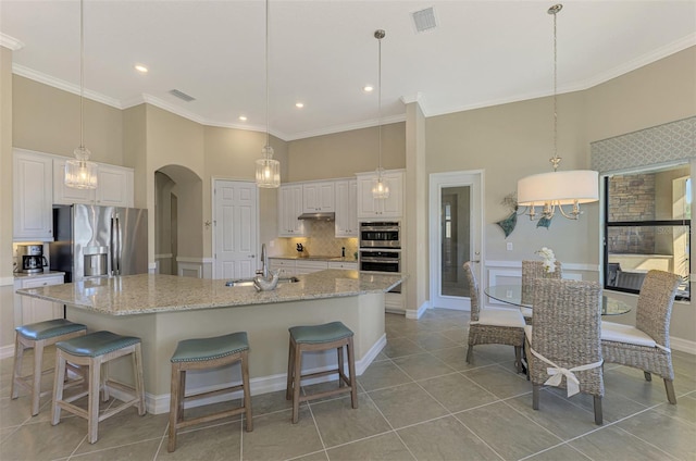 kitchen with a spacious island, white cabinetry, hanging light fixtures, and appliances with stainless steel finishes