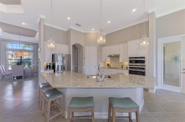 kitchen with a large island, sink, white cabinets, and stainless steel appliances