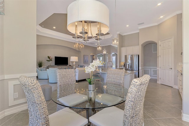 tiled dining space with a raised ceiling, crown molding, and a notable chandelier