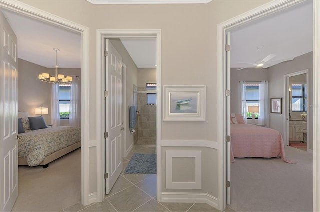 hall featuring a chandelier, light colored carpet, and a healthy amount of sunlight