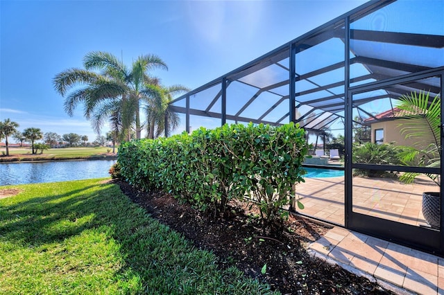 exterior space with glass enclosure, a yard, and a water view