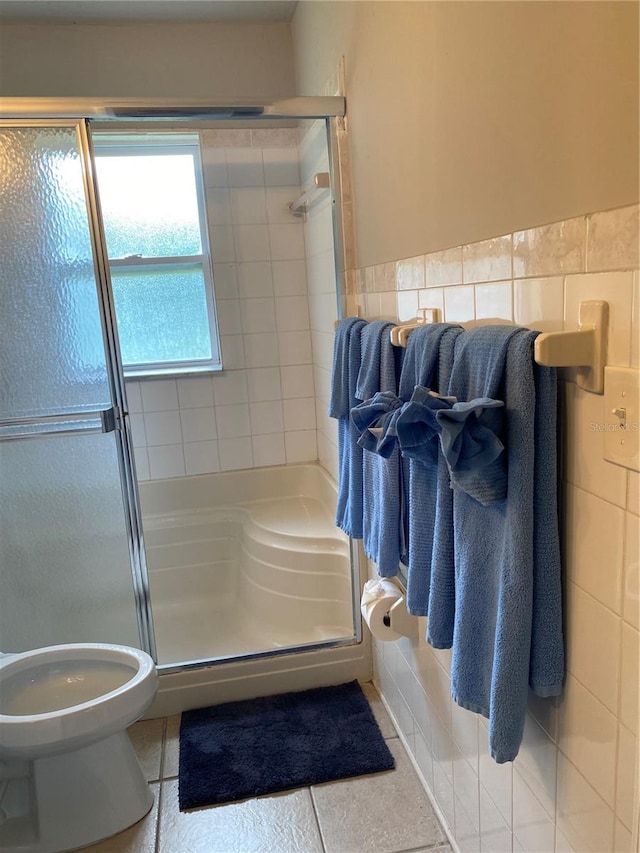 bathroom with tile patterned flooring, a shower with door, and tile walls