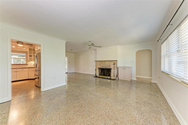 unfurnished living room featuring ceiling fan and a fireplace