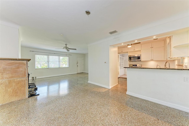 unfurnished living room featuring ceiling fan and sink