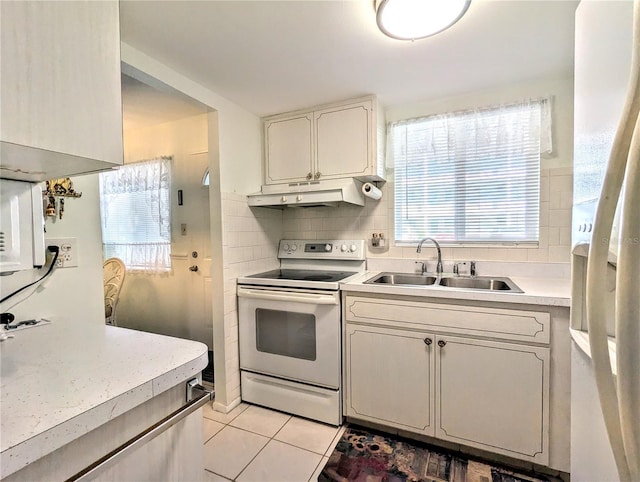 kitchen featuring sink, electric range oven, white refrigerator with ice dispenser, backsplash, and light tile patterned flooring