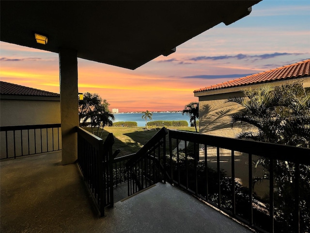 balcony at dusk featuring a water view