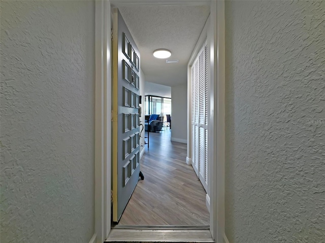 corridor with wood-type flooring and a textured ceiling