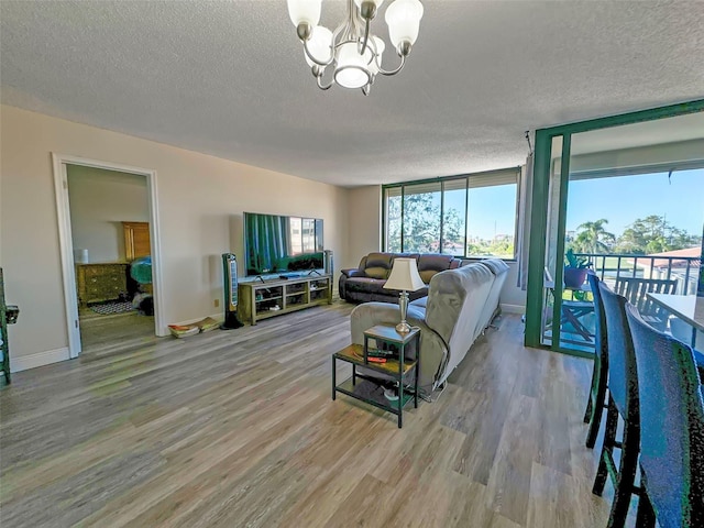 living room featuring light hardwood / wood-style floors, a textured ceiling, and an inviting chandelier