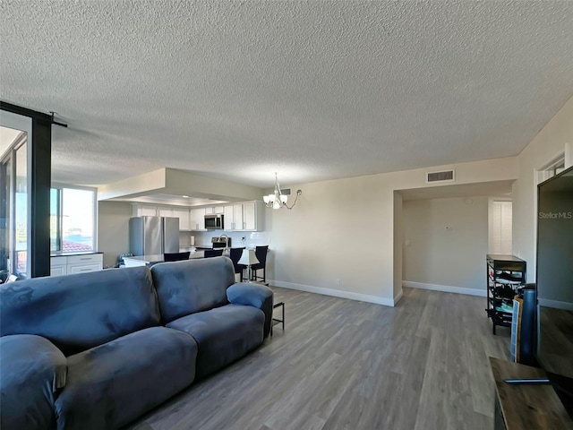 living room with a textured ceiling, light hardwood / wood-style flooring, and a notable chandelier