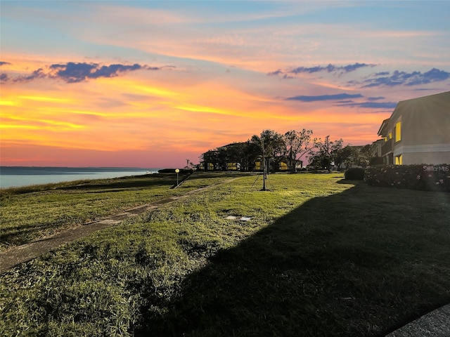 yard at dusk featuring a water view