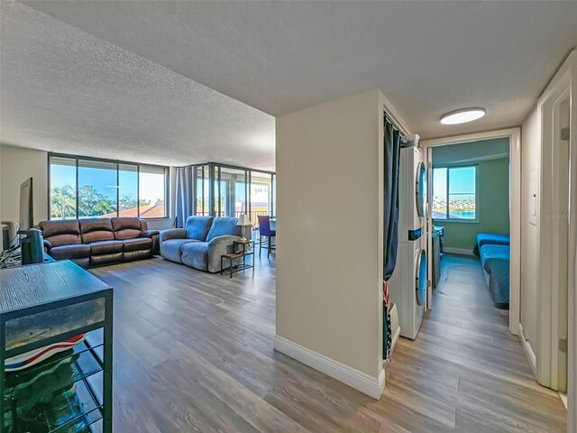 living area featuring plenty of natural light, baseboards, a textured ceiling, and wood finished floors