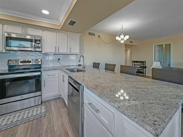 kitchen with stainless steel appliances, a sink, visible vents, white cabinetry, and light wood finished floors