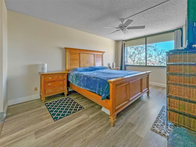 bedroom featuring a textured ceiling, wood finished floors, and baseboards