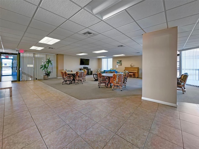 unfurnished dining area featuring light tile patterned flooring, a paneled ceiling, light carpet, visible vents, and baseboards