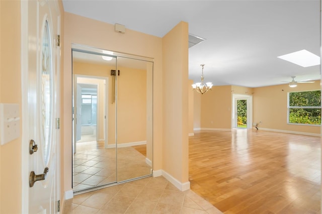 corridor with a notable chandelier, a skylight, and light hardwood / wood-style flooring