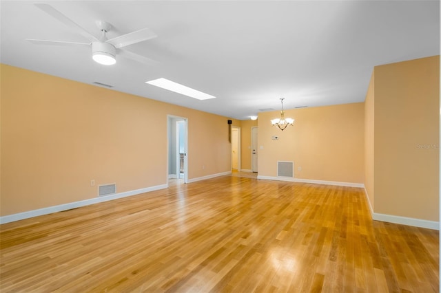 spare room with ceiling fan with notable chandelier and light hardwood / wood-style flooring