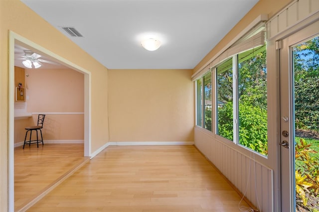 unfurnished sunroom featuring ceiling fan and a wealth of natural light