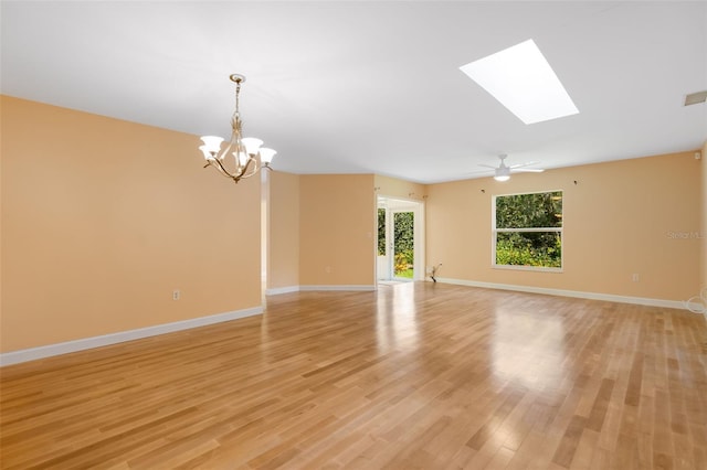 spare room featuring ceiling fan with notable chandelier, light hardwood / wood-style floors, and a skylight