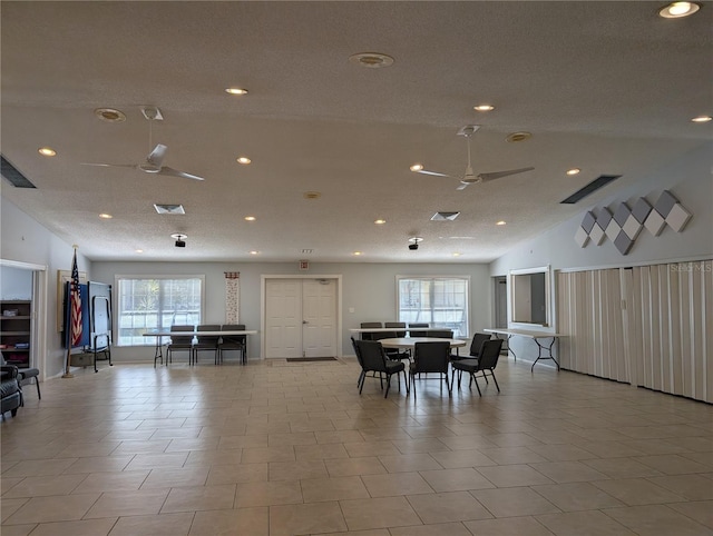 tiled dining area with vaulted ceiling, ceiling fan, a healthy amount of sunlight, and a textured ceiling