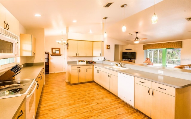 kitchen featuring hanging light fixtures, white appliances, open floor plan, and a sink