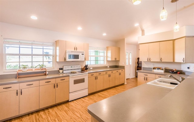 kitchen with light wood-style flooring, white appliances, a sink, light countertops, and pendant lighting