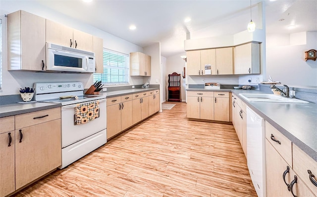 kitchen with white appliances, hanging light fixtures, light wood-type flooring, a sink, and recessed lighting