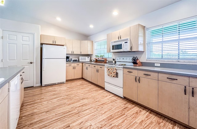 kitchen with lofted ceiling, light countertops, white appliances, and light wood-style flooring