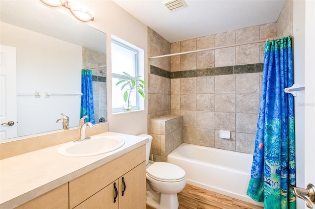 bathroom with visible vents, toilet, shower / tub combo with curtain, wood finished floors, and vanity