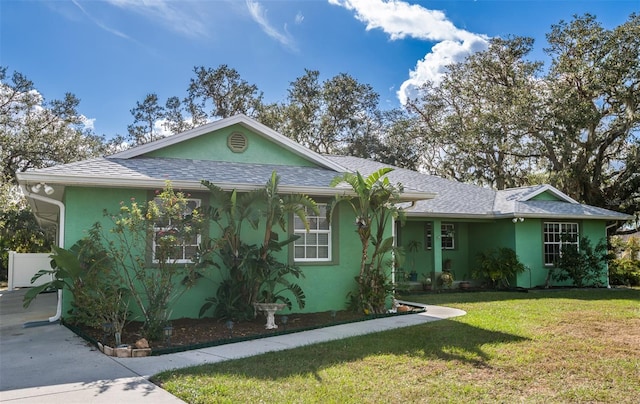 single story home with stucco siding, roof with shingles, and a front yard