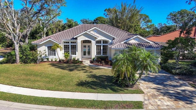 mediterranean / spanish home with a front yard and french doors