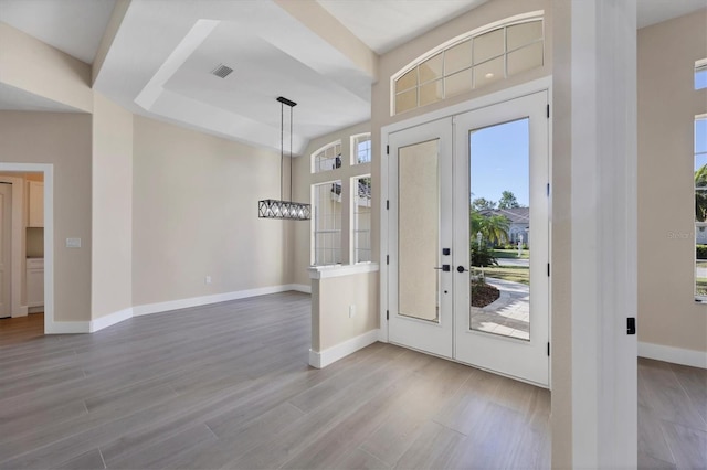 entryway featuring french doors, light wood-type flooring, and a notable chandelier